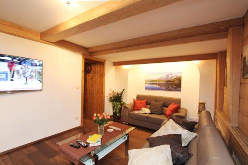 a living room with a couch and a tv at Gästehaus Sonnenheim in Mittenwald