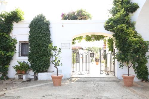 an entrance to a white building with a gate and plants at Masseria Parco di Castro in Montalbano