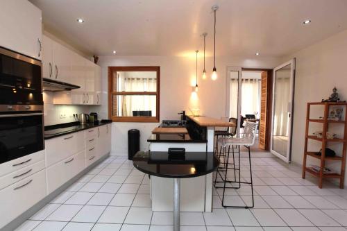 une cuisine avec des armoires blanches et une table à l'intérieur dans l'établissement Deluxe and luminous apartment front of the sea, à Capbreton