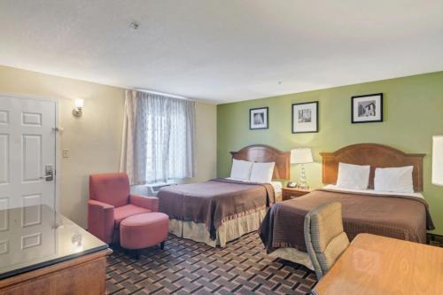 une chambre d'hôtel avec deux lits et une chaise dans l'établissement Savannah Garden Hotel, à Savannah