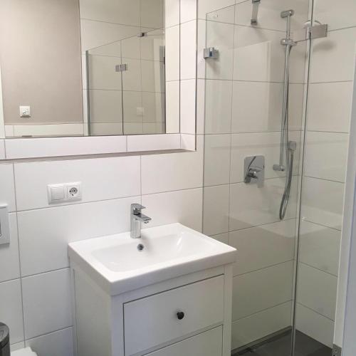 a white bathroom with a sink and a shower at Gästehaus Engelgarten in Estenfeld