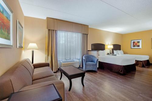 La Quinta Inn & Suites Bel Air في بل آير: غرفه فندقيه بسرير واريكه