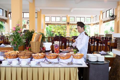 a chef standing in front of a table with food at Hon Rom Central Beach Resort in Mui Ne