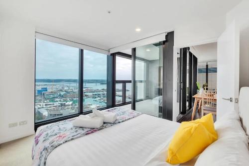 a bedroom with a large white bed and large windows at Amazing Harbour, Skytower and Rangitoto Views in Auckland
