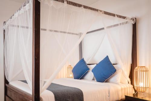 a bedroom with a canopy bed with blue pillows at The C Samet Beach Resort SHA Plus in Ko Samed