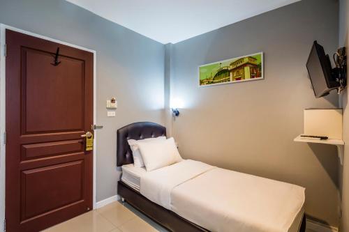 a small room with a bed and a door at At Hua Lamphong Hotel in Bangkok