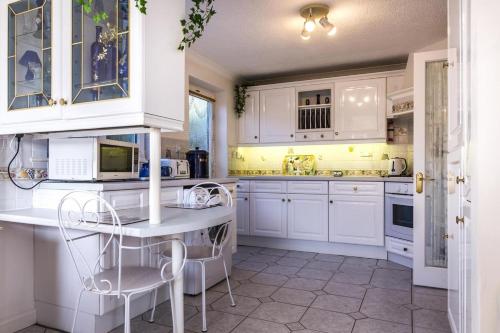 a white kitchen with white cabinets and appliances at Family Bungalow with Private Pool in Kilgetty