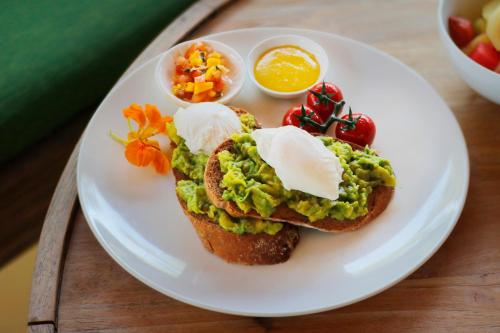 a plate of food with eggs and bread and fruit at The Jineng Villas by Ekosistem in Seminyak