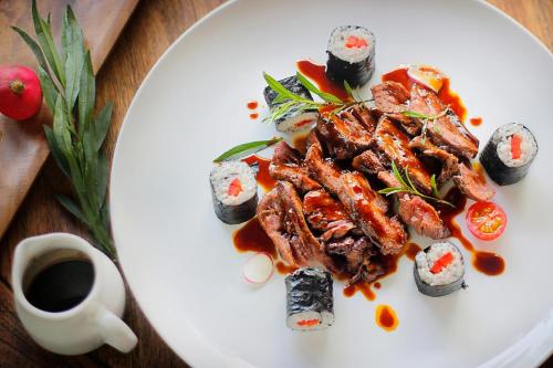 a white plate of food with sushi on a table at The Jineng Villas by Ekosistem in Seminyak
