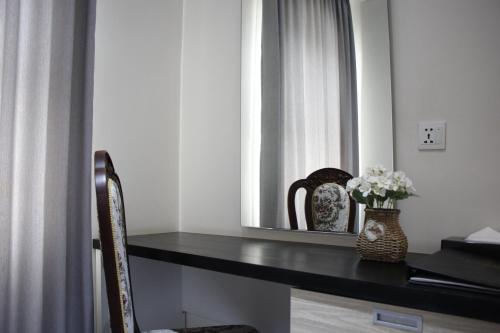 a desk with a mirror and a vase of flowers at LCS Hotel & Apartment in Phnom Penh