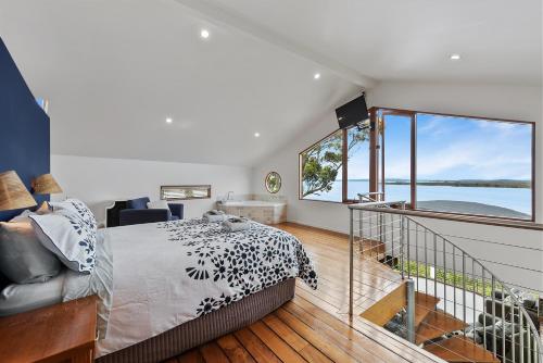 a bedroom with a bed and a large window at Wheelhouse Apartments in Strahan