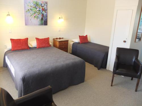 a hotel room with two beds and a chair at Colonial Court Motel in Cambridge
