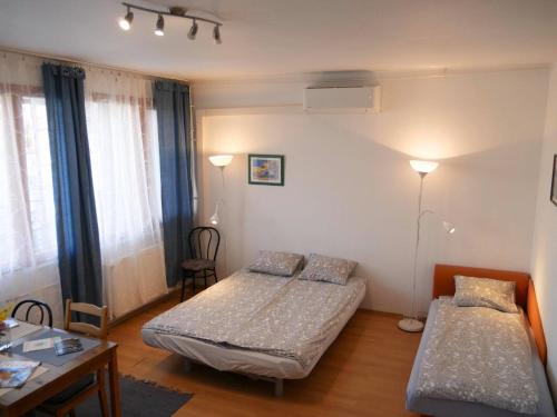 ブダペストにあるCasaLara-Cozy Nest Near Buda Castleのベッド2台、テーブル、ランプ2つが備わる客室です。
