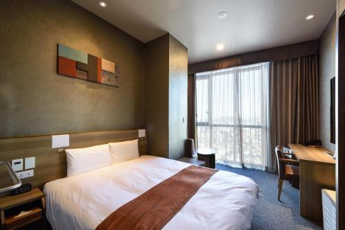 a hotel room with a bed and a desk and a window at Dormy Inn SEOUL Gangnam in Seoul