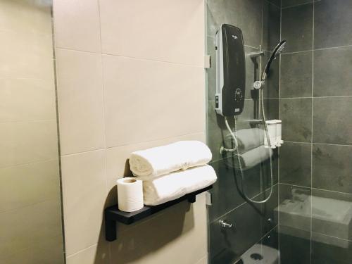 a bathroom with a shower with towels on a shelf at Enclave Hotel in Putrajaya