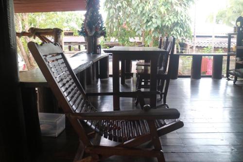 a group of chairs sitting around a table on a porch at Baanmakpoo บ้านหมากพลู in Sangkhla Buri
