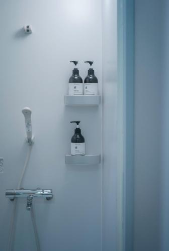 a bathroom with three bottles of soap on shelves at FOLK FOLK Hostel, Cafe & Bar in Ise