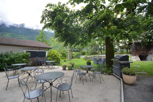 a patio with tables and chairs under a tree at Le Relais Du Mont Blanc in Magland