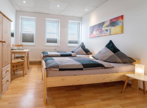 um quarto com 2 camas, uma secretária e janelas em Pension Schweizer em Laupheim