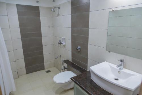 uma casa de banho com um lavatório, um WC e um espelho. em Ginger Agartala em Agartala