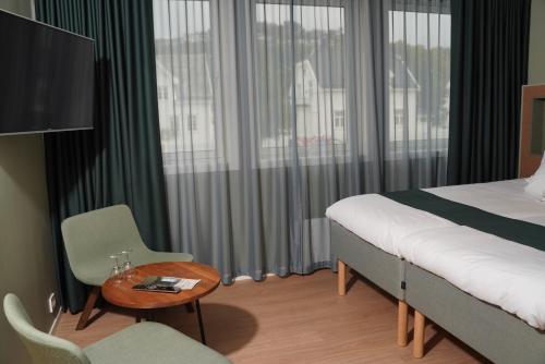 a hotel room with a bed and a table and a chair at Maritim Fjordhotel in Flekkefjord