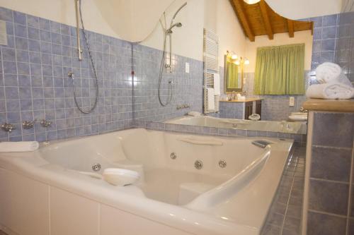 y baño de azulejos azules con bañera blanca grande. en Hotel Adda, en Spino dʼAdda