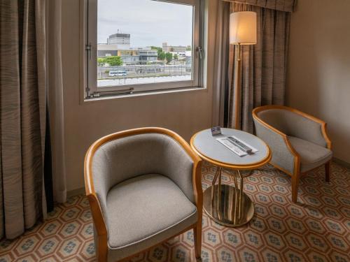 a room with two chairs and a table and a window at Hotel Nikko Tsukuba in Tsukuba