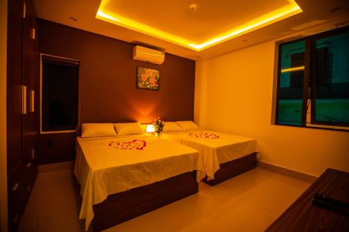 a bedroom with two beds with white sheets at Bamboo Green Hotel in Dong Hoi