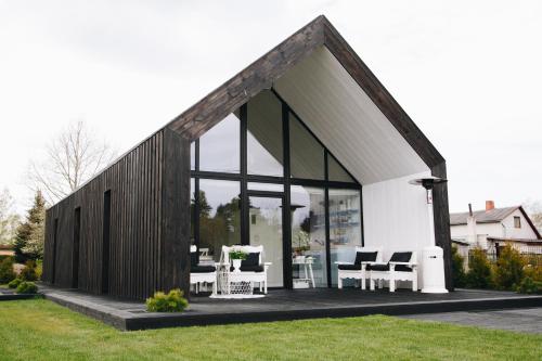 a house with glass doors and white chairs in a yard at RELAX PORT in Bigauņciems