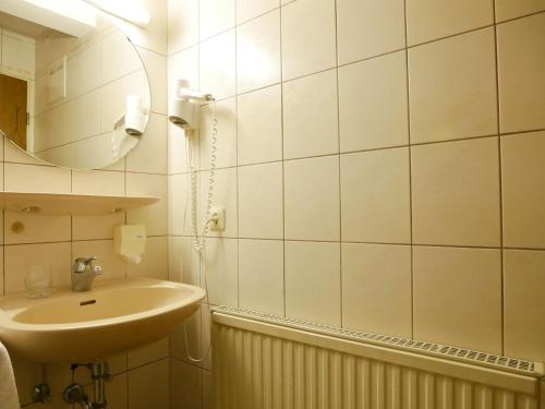 a white bathroom with a sink and a mirror at Gasthaus Engel in Bühlertal