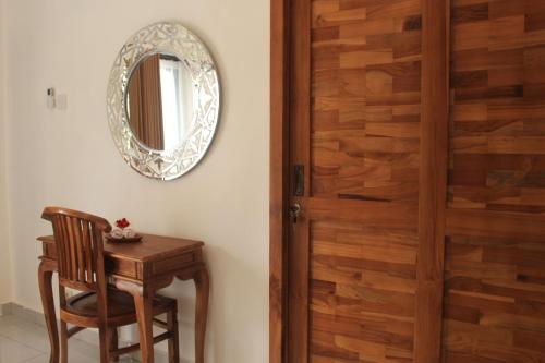 a wooden door in a room with a table and a mirror at Intan Guest House in Ubud