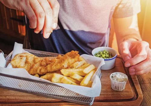 a person holding a tray of fish and french fries at Holiday Inn Dhaka City Centre by IHG in Dhaka