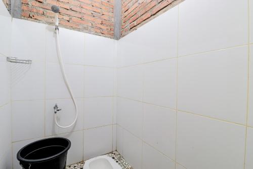 ein weiß gefliestes Bad mit einem WC und einer Dusche in der Unterkunft d'Hasinda Homestay in Magelang