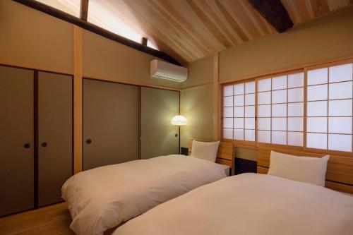 a bedroom with two beds and a window at Ayaginu Machiya House in Kyoto