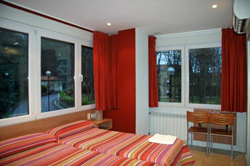 a bedroom with a bed and windows with red curtains at Ekia Pentsioa in Zarautz