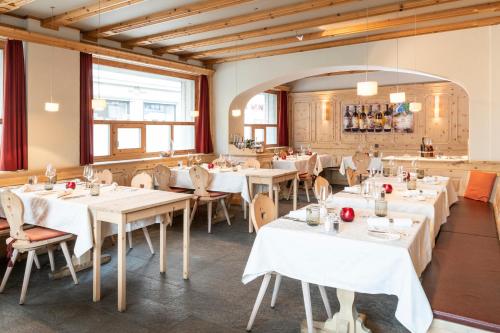 a dining room with white tables and chairs at Hotel Donatz in Samedan