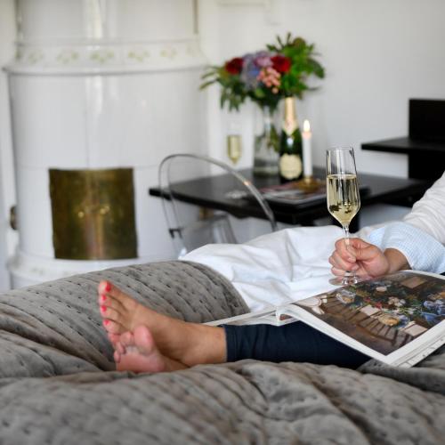 a person sitting on a couch with a glass of wine at Huskvarna Stadshotell in Huskvarna