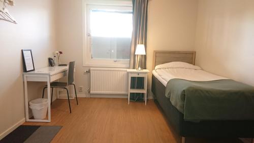 a bedroom with a bed and a desk and a window at Övik Eventhotell in Örnsköldsvik