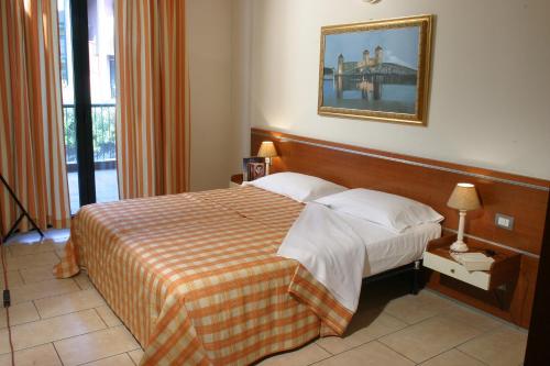 una camera d'albergo con un letto e una foto appesa alla parete di Residence Spiaggia D'Oro a Desenzano del Garda
