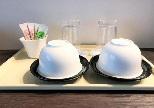 two cups on a tray with chopsticks and glasses at Hotel Okus in Kumamoto