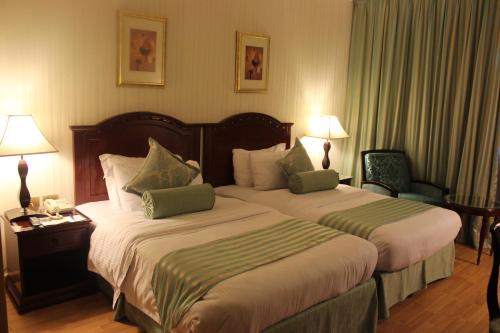 a hotel room with two beds and two lamps at Swiss Al Hamra Hotel in Dammam