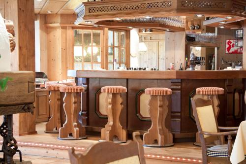 a bar in a restaurant with wooden bar stools at Suitehotel Kleinwalsertal in Hirschegg