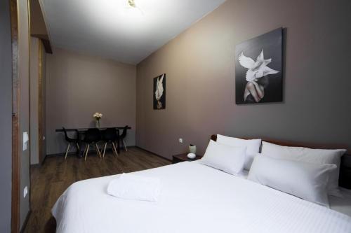Un dormitorio con una gran cama blanca y una mesa. en Апартаменти на площі Митній, en Leópolis