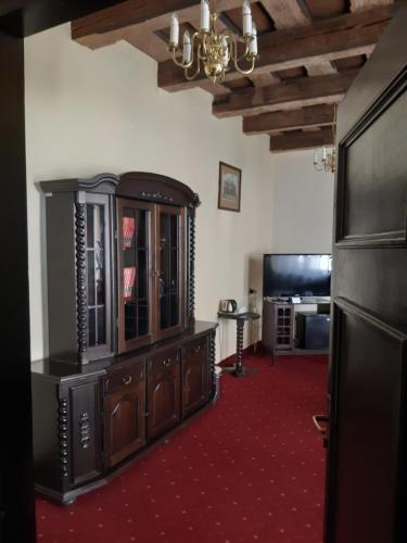 a living room with a wooden cabinet and a television at Hotel Dwór Polski in Wrocław