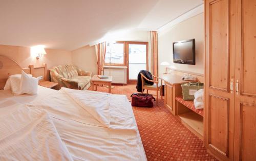ヒルシュエックにあるSuitehotel Kleinwalsertalのベッドとデスクが備わるホテルルームです。