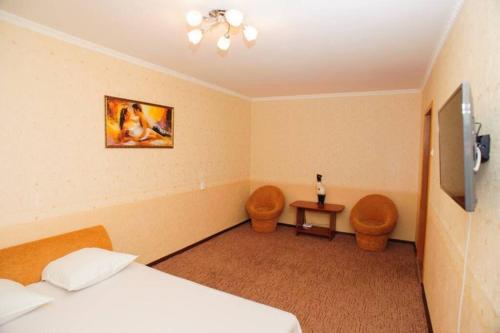 - une chambre avec un lit, deux chaises et une télévision dans l'établissement Тараскова 4, à Tcherkassy
