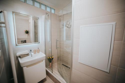 a white bathroom with a sink and a shower at Apartmán Tatranská Lomnica in Tatranská Lomnica