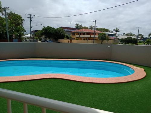 a large swimming pool with green grass around it at Ocean View 3 bedroom Apartment in Mudjimba