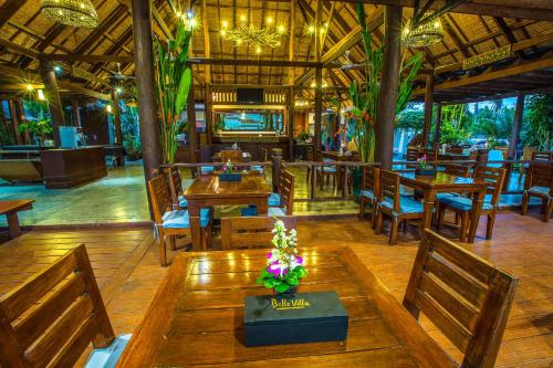 een restaurant met houten tafels en stoelen en een televisie bij Belle Villa Resort, Pai in Pai