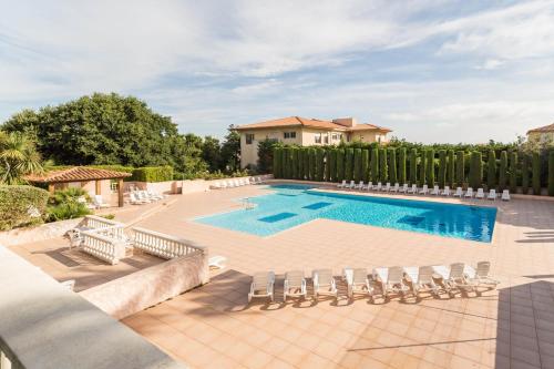 une piscine avec des chaises longues et une clôture dans l'établissement Résidence Pierre & Vacances Eden Parc, à Saint-Tropez